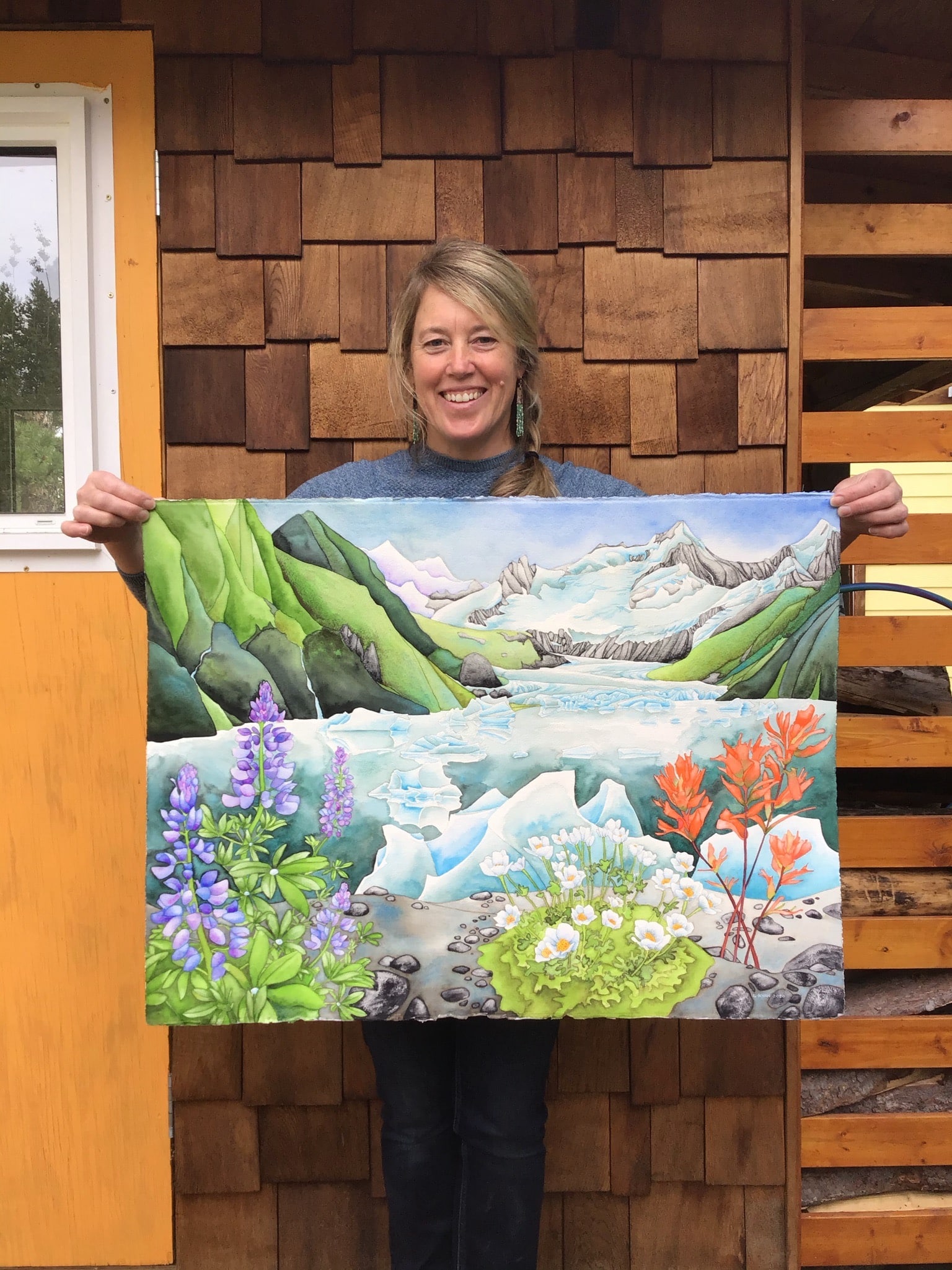 The artist holding a large watercolor made in Skagway