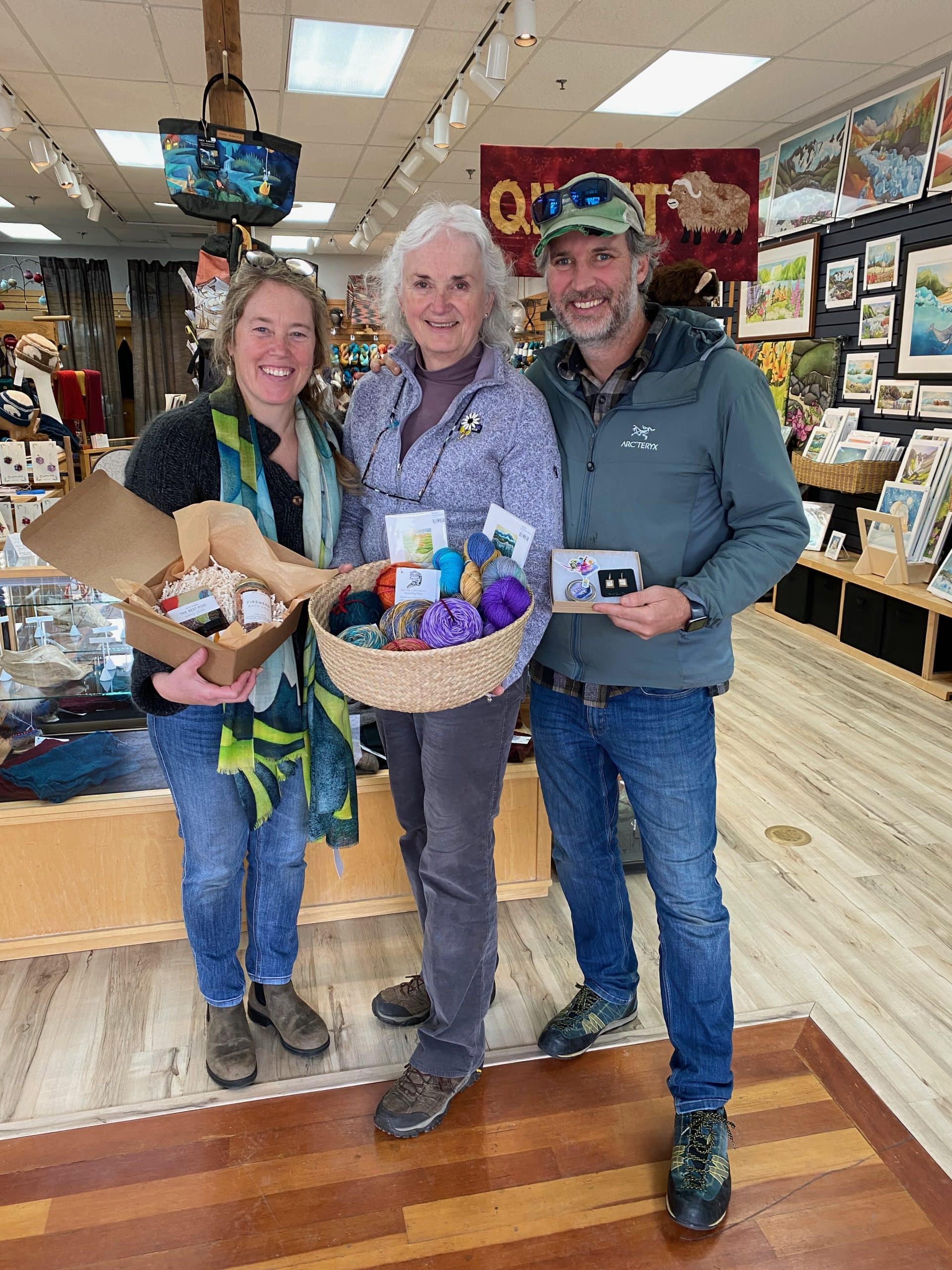Three people holding locally made gifts in their shop